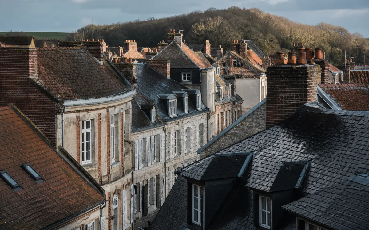 Alignement de toitures en brique et ardoise dans les Hauts-de-France sous une lumière douce